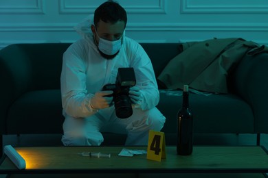 Photo of Forensic expert with camera taking photo of evidences at crime scene in dark room