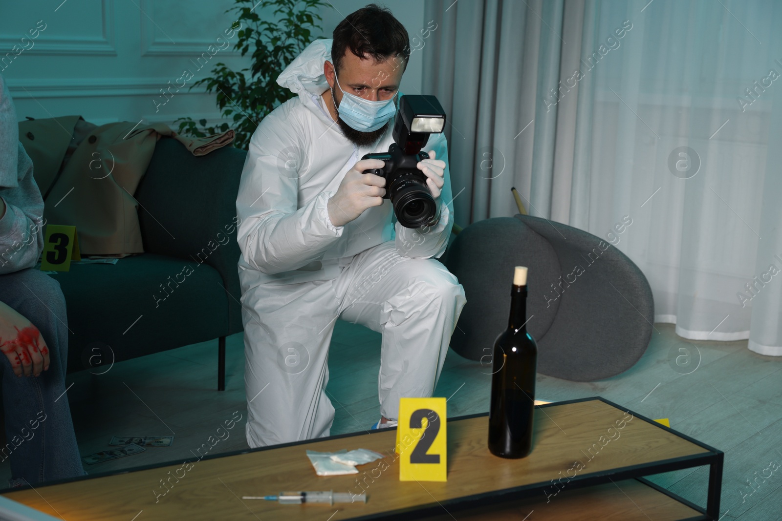 Photo of Forensic expert with camera working and victim at crime scene indoors