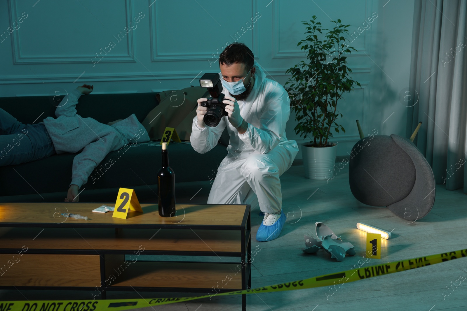 Photo of Forensic expert with camera working at crime scene and dead woman's body indoors