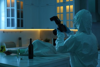 Photo of Forensic expert with camera working at crime scene and dead woman's body in dark room