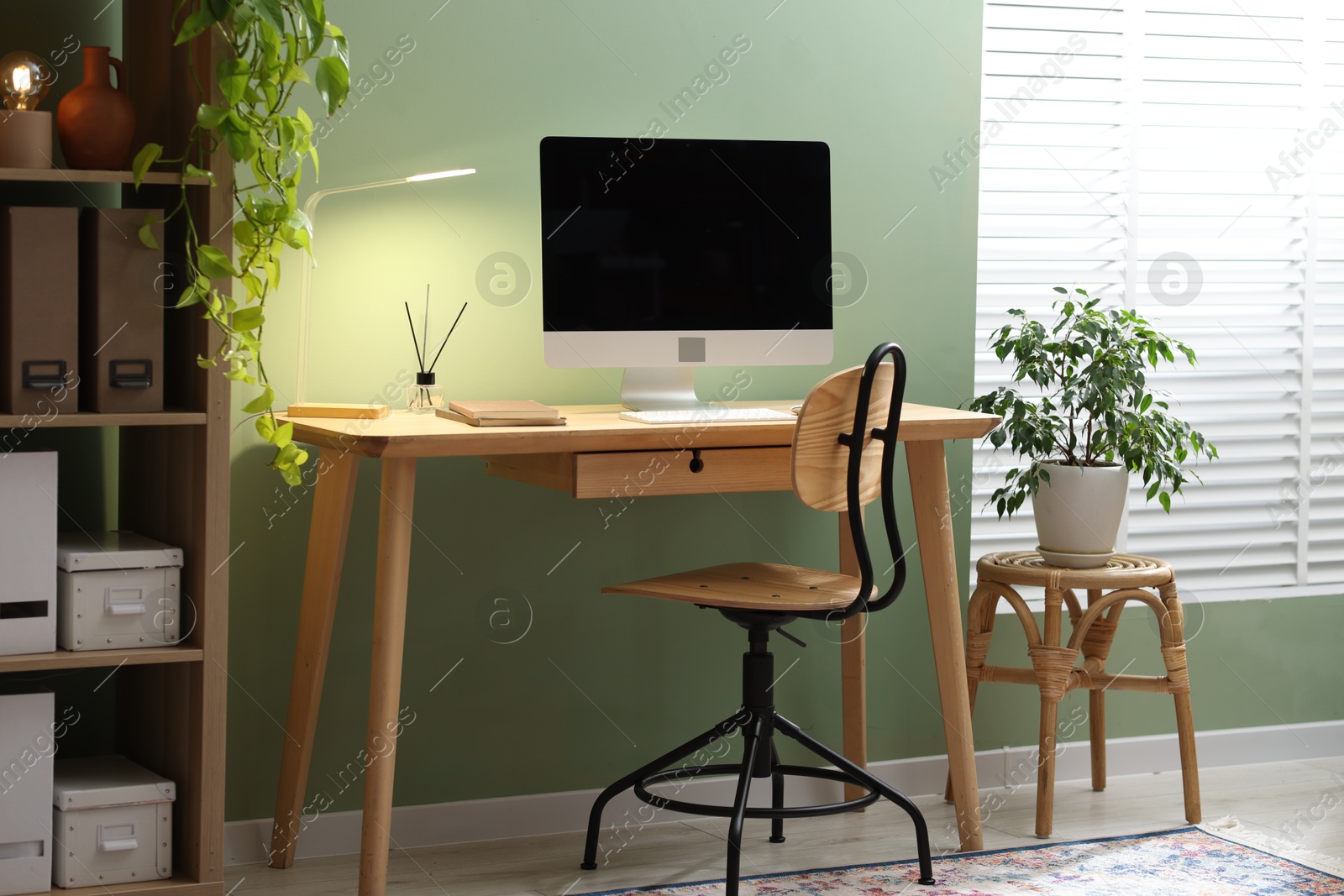 Home office. Comfortable workplace near light green wall. Desk with computer and other furniture in room Photo of Home office. Comfortable workplace near light green wall. Desk with computer and other furniture in room