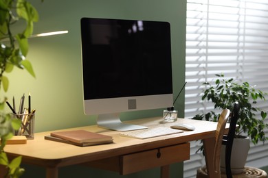 Photo of Comfortable workplace with computer and stationery on wooden desk in home office