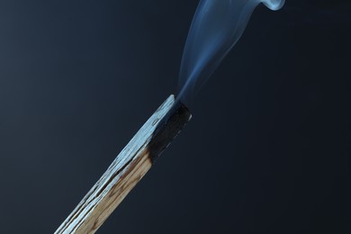 Photo of Smoldering palo santo stick against grey background, closeup