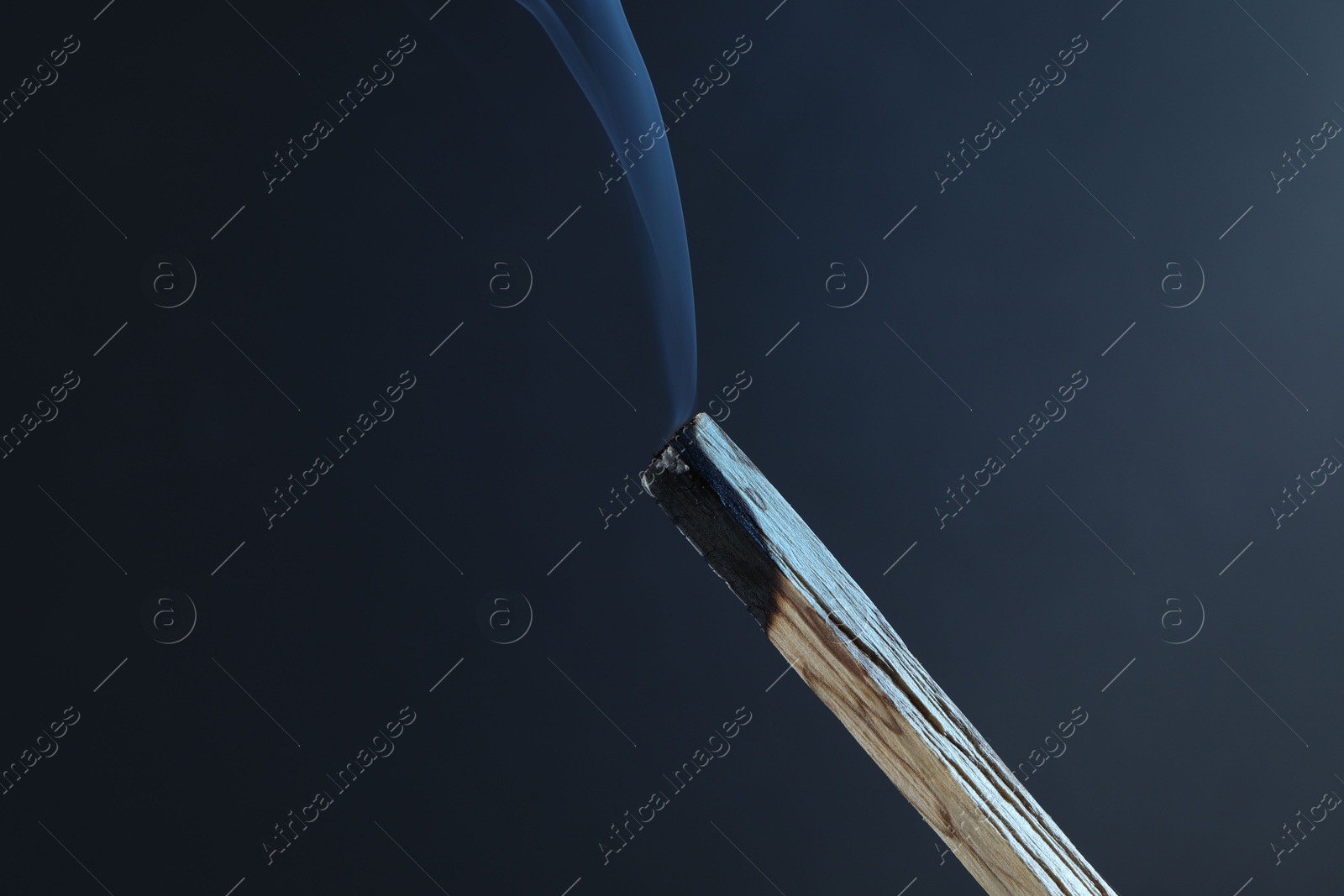 Photo of Smoldering palo santo stick against grey background, closeup