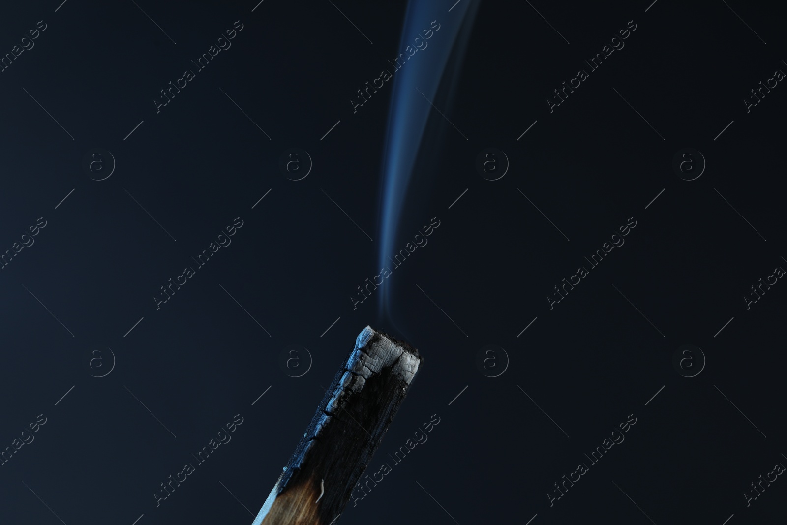 Photo of Smoldering palo santo stick against grey background, closeup