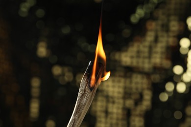 Photo of Burning palo santo stick against blurred background, closeup