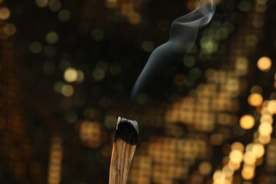 Photo of Smoldering palo santo stick against blurred background, closeup