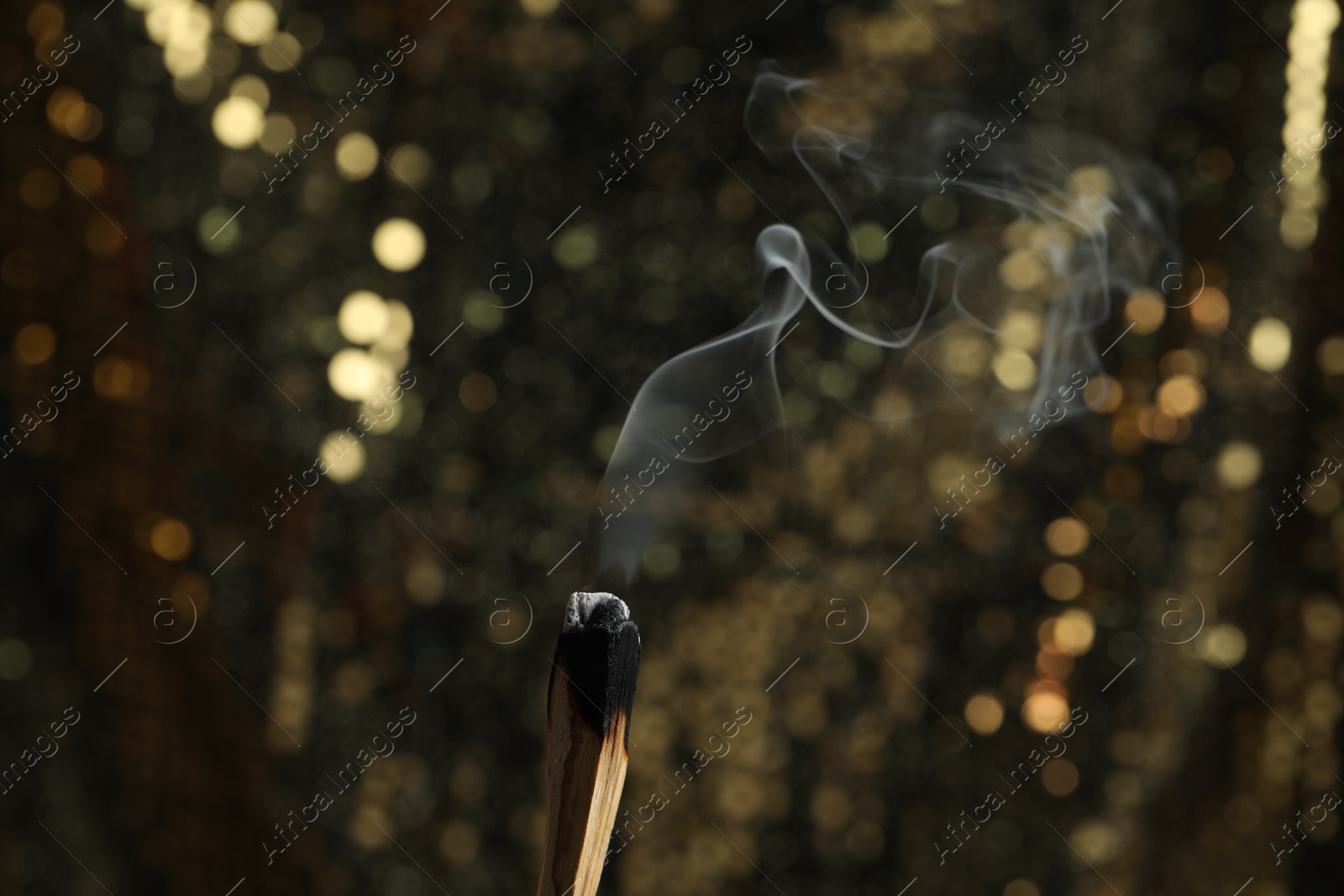 Photo of Smoldering palo santo stick against blurred background, closeup