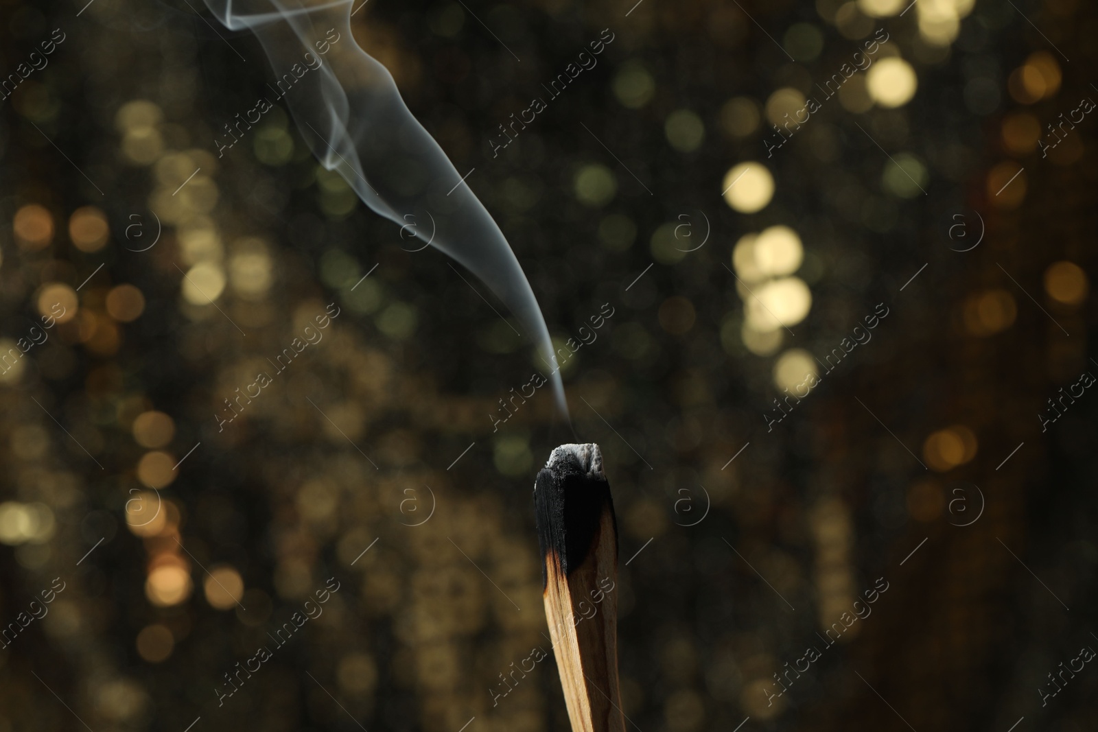 Photo of Smoldering palo santo stick against blurred background, closeup