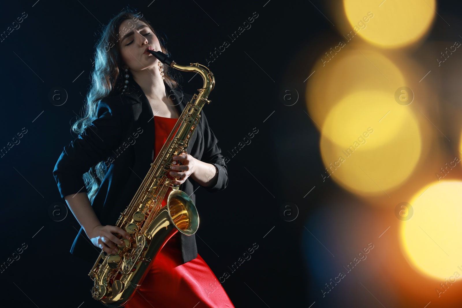 Photo of Professional musician playing saxophone on black background with blurred lights. Bokeh effect