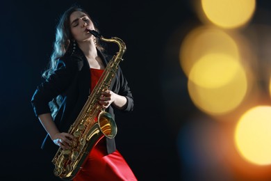 Photo of Professional musician playing saxophone on black background with blurred lights. Bokeh effect