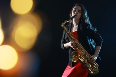 Photo of Professional musician playing saxophone on black background with blurred lights. Bokeh effect