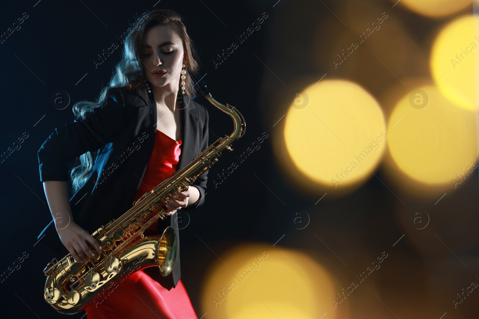 Photo of Professional musician playing saxophone on black background with blurred lights. Bokeh effect