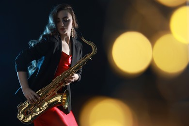 Photo of Professional musician playing saxophone on black background with blurred lights. Bokeh effect