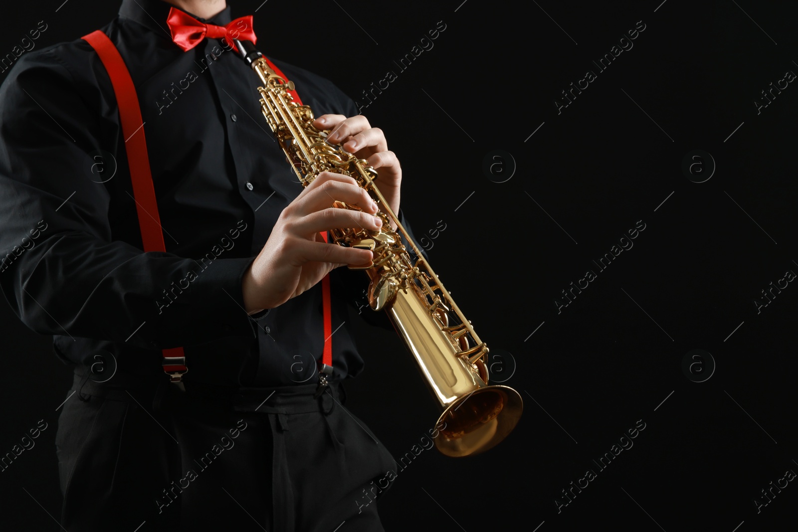 Photo of Professional musician playing soprano saxophone on black background, closeup. Space for text