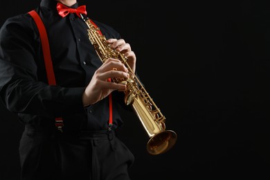 Photo of Professional musician playing soprano saxophone on black background, closeup. Space for text