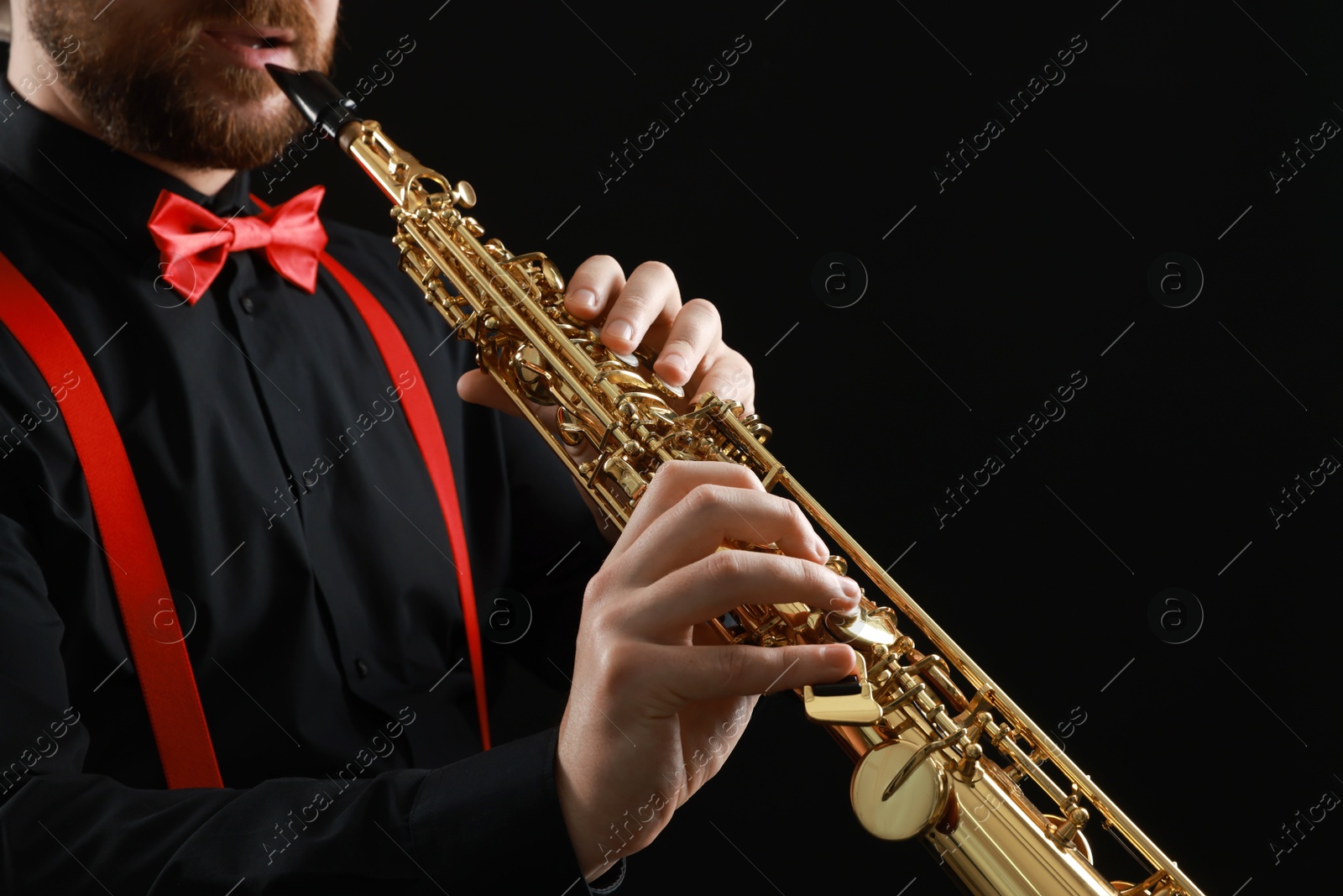 Photo of Professional musician playing soprano saxophone on black background, closeup. Space for text