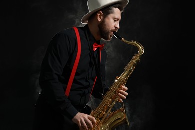 Photo of Professional musician playing saxophone on black background with smoke