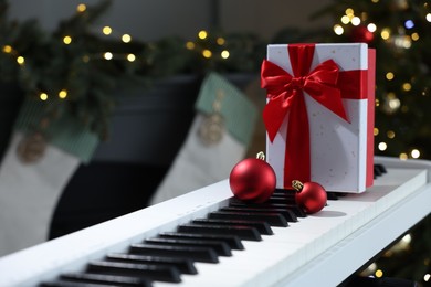 Photo of Gift and Christmas ornaments on piano against blurred lights, closeup. Bokeh effect