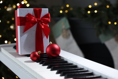 Photo of Gift and Christmas ornaments on piano against blurred lights, closeup. Bokeh effect