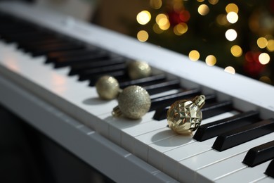 Photo of Christmas ornaments on electric piano against blurred lights, closeup. Bokeh effect