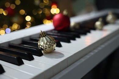 Photo of Christmas ornaments on electric piano against blurred lights, closeup. Bokeh effect