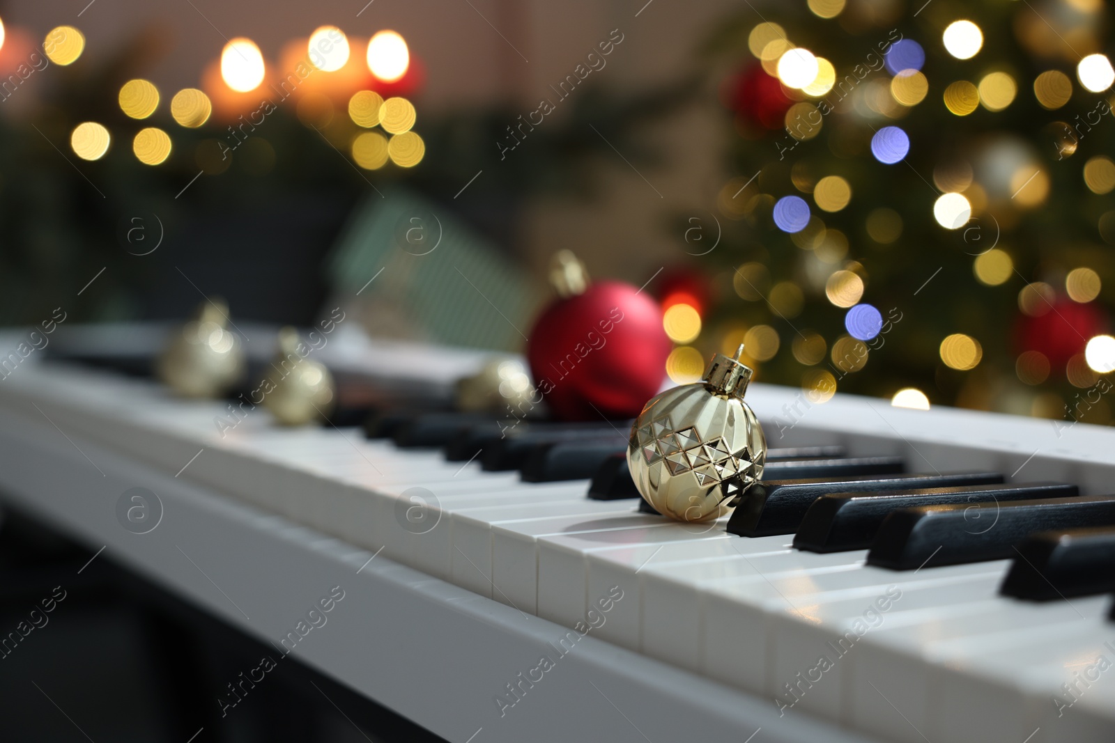 Photo of Christmas ornaments on electric piano against blurred lights, closeup. Bokeh effect