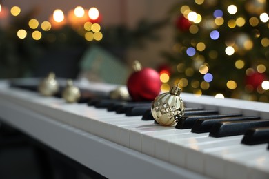 Christmas ornaments on electric piano against blurred lights, closeup. Bokeh effect