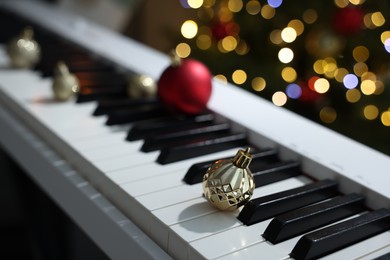 Photo of Christmas ornaments on electric piano against blurred lights, closeup. Bokeh effect