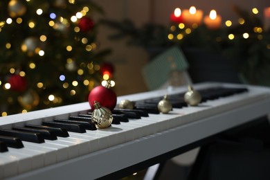 Photo of Christmas ornaments on electric piano against blurred lights, closeup. Bokeh effect