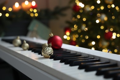 Photo of Christmas ornaments on electric piano against blurred lights, closeup. Bokeh effect