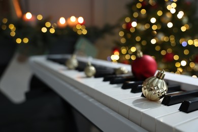 Photo of Christmas ornaments on electric piano against blurred lights, closeup. Bokeh effect