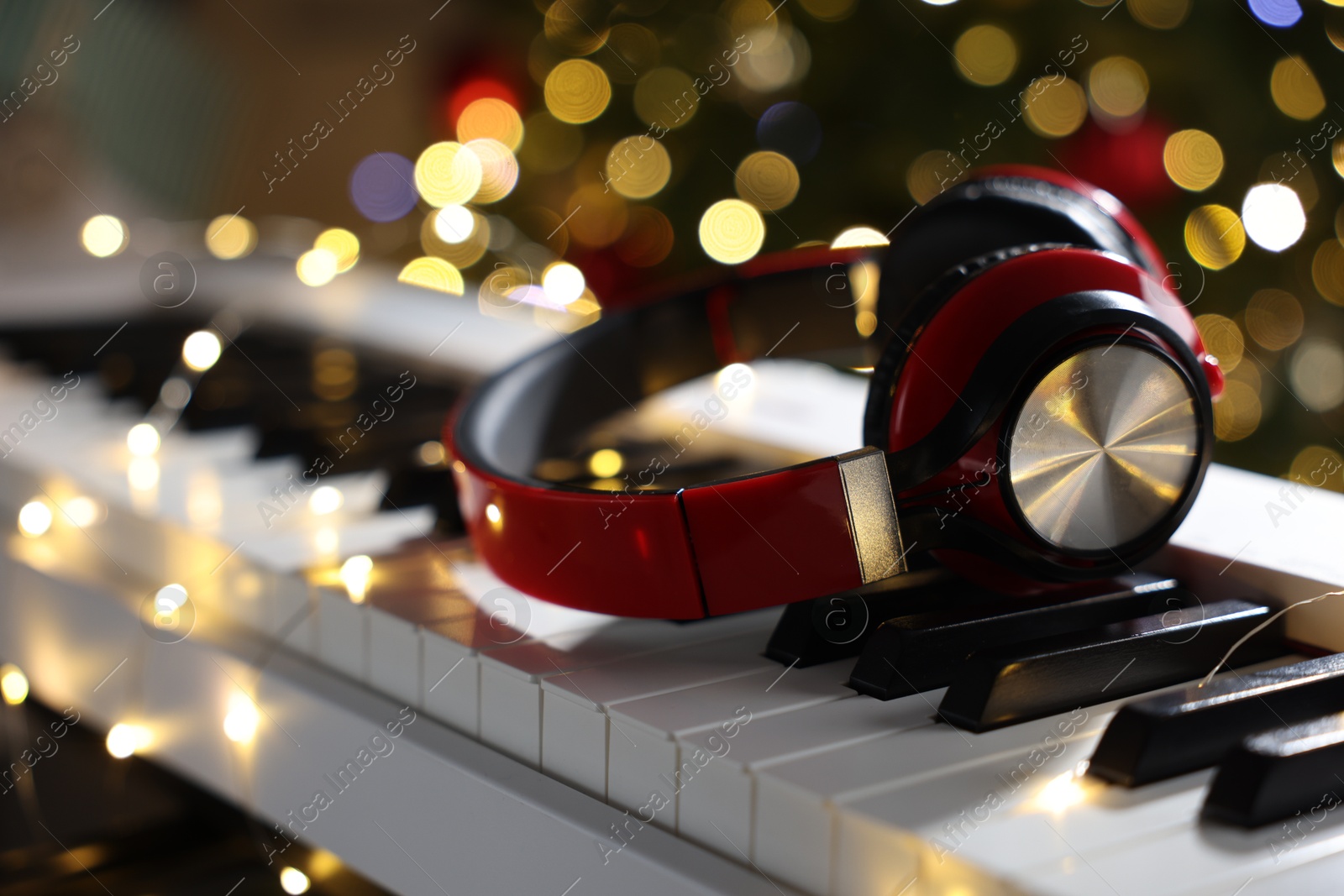 Headphones on electric piano against Christmas tree with blurred lights, closeup. Bokeh effect Photo of Headphones on electric piano against Christmas tree with blurred lights, closeup. Bokeh effect