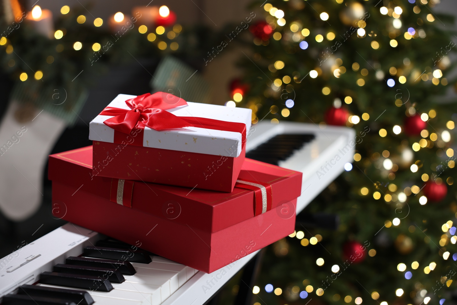 Gifts on electric piano against Christmas tree with blurred lights, closeup. Bokeh effect Photo of Gifts on electric piano against Christmas tree with blurred lights, closeup. Bokeh effect