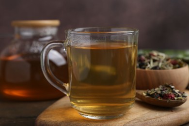 Photo of Delicious herbal tea and dry leaves on wooden table, closeup