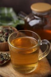 Photo of Delicious herbal tea and dry leaves on wooden table, closeup