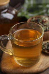 Photo of Delicious herbal tea and dry leaves on wooden table, closeup