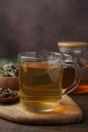 Photo of Delicious herbal tea and dry leaves on wooden table