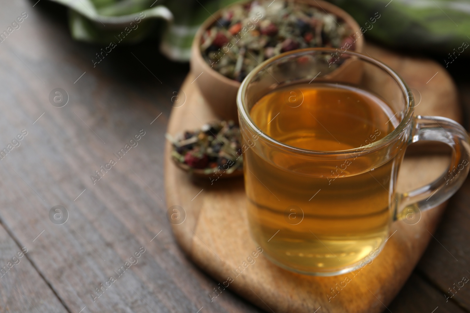 Photo of Delicious herbal tea and dry leaves on wooden table, closeup. Space for text