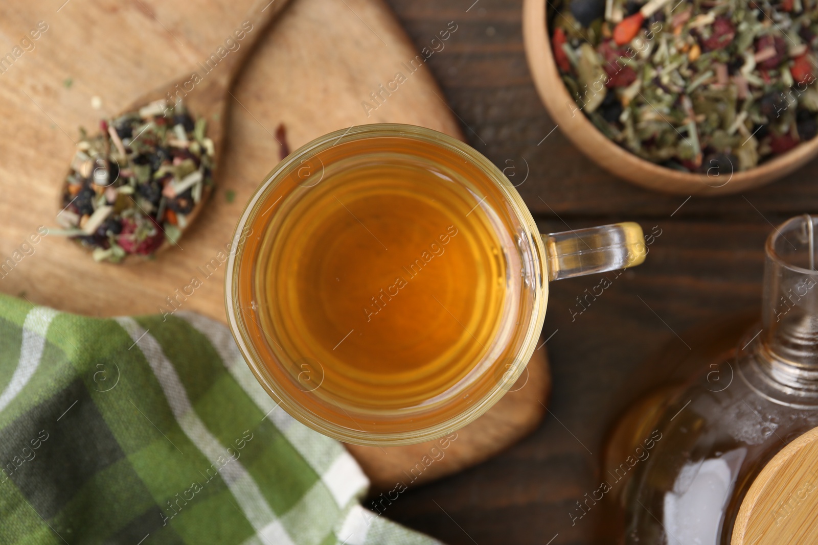 Photo of Delicious herbal tea and dry leaves on wooden table, flat lay