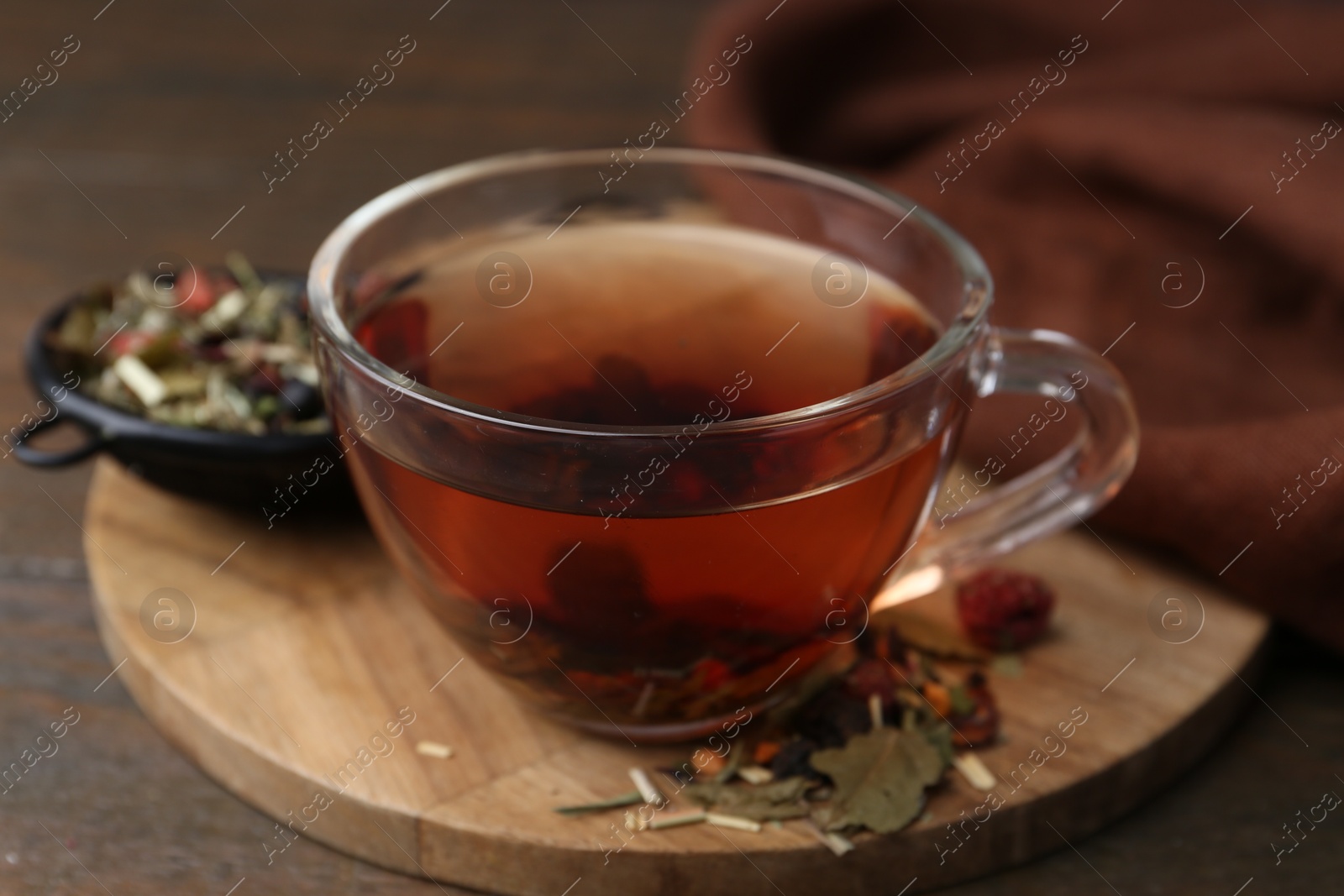 Photo of Delicious herbal tea and dry leaves on wooden table, closeup