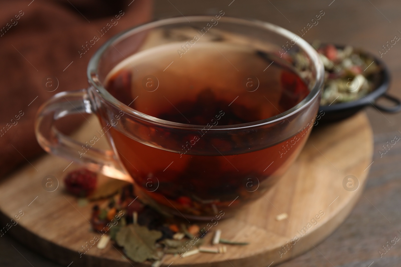 Photo of Delicious herbal tea and dry leaves on wooden table, closeup