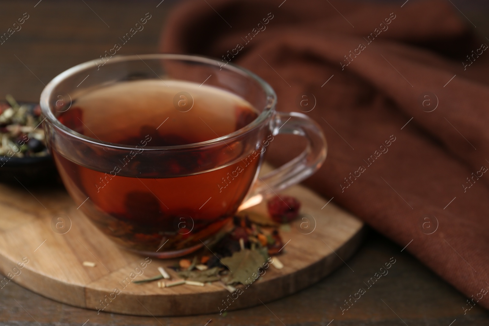 Photo of Delicious herbal tea and dry leaves on wooden table, closeup. Space for text