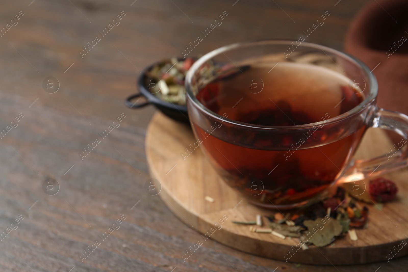 Photo of Delicious herbal tea and dry leaves on wooden table, closeup. Space for text