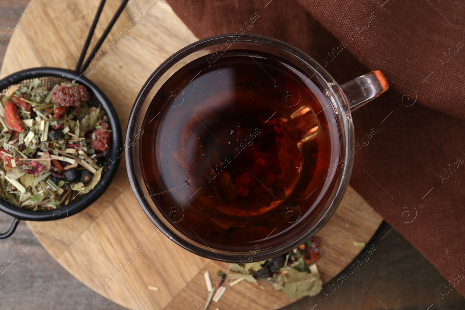 Photo of Delicious herbal tea and dry leaves on wooden table, top view