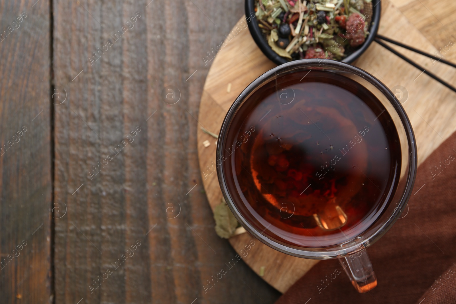 Photo of Delicious herbal tea and dry leaves on wooden table, top view. Space for text