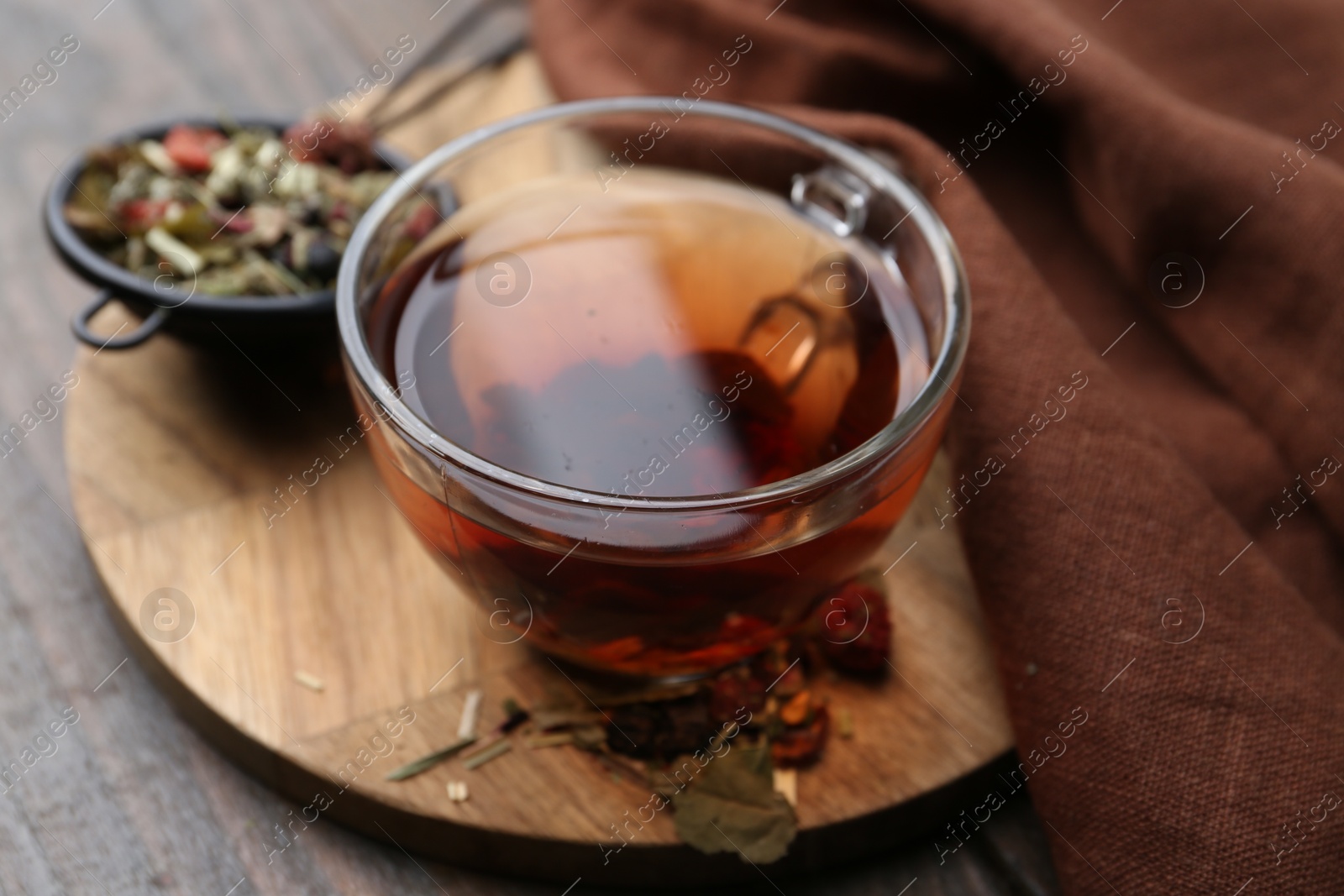 Photo of Delicious herbal tea and dry leaves on wooden table, closeup