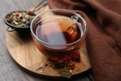 Photo of Delicious herbal tea and dry leaves on wooden table, closeup