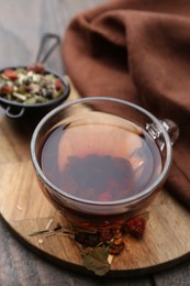 Photo of Delicious herbal tea and dry leaves on wooden table, closeup