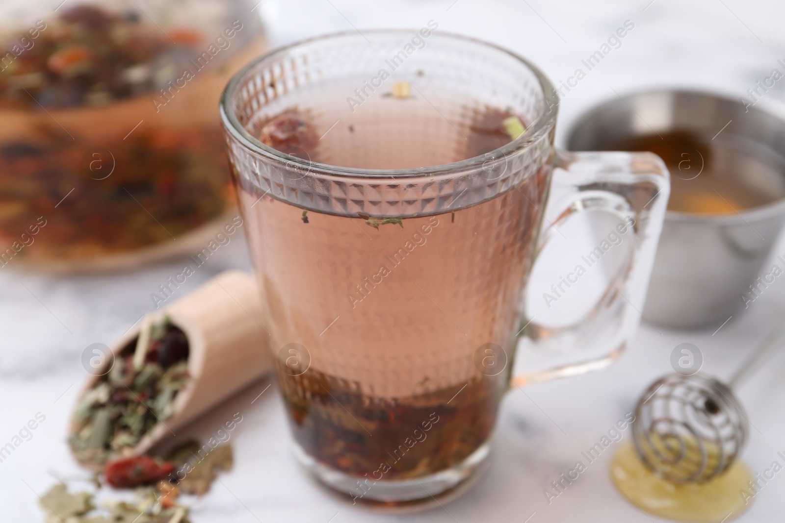 Photo of Delicious herbal tea with honey and dry leaves on white marble table, closeup